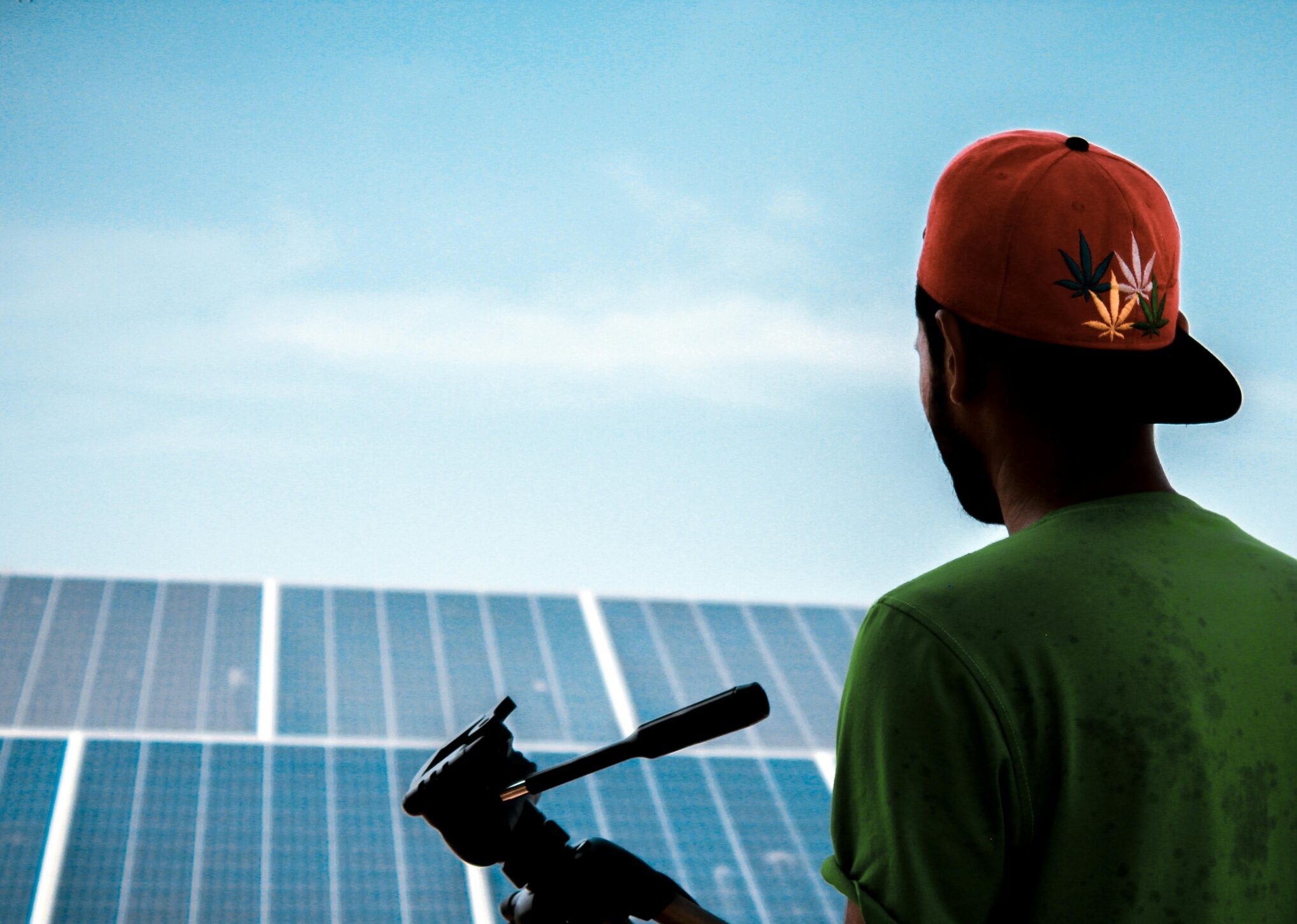 A person in a cap films a solar panel installation, promoting sustainable energy solutions.